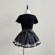 Back view of the Lolita dress, showing black puff sleeves, a checked waist bow, and white lace around the hem.