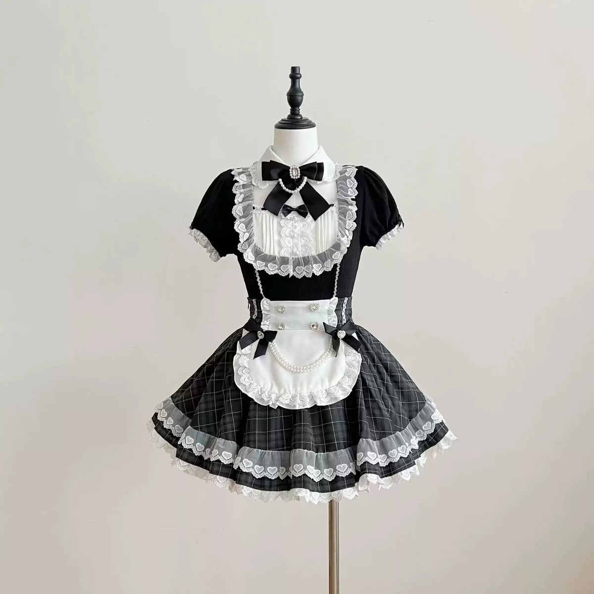 Front view of a black and white lace Lolita dress with puff sleeves, a white apron, and a flared checked skirt.