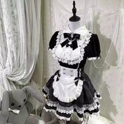 Angled mannequin view of the black and white Lolita dress with bow accents, a white apron, and a lace-trimmed checked skirt.